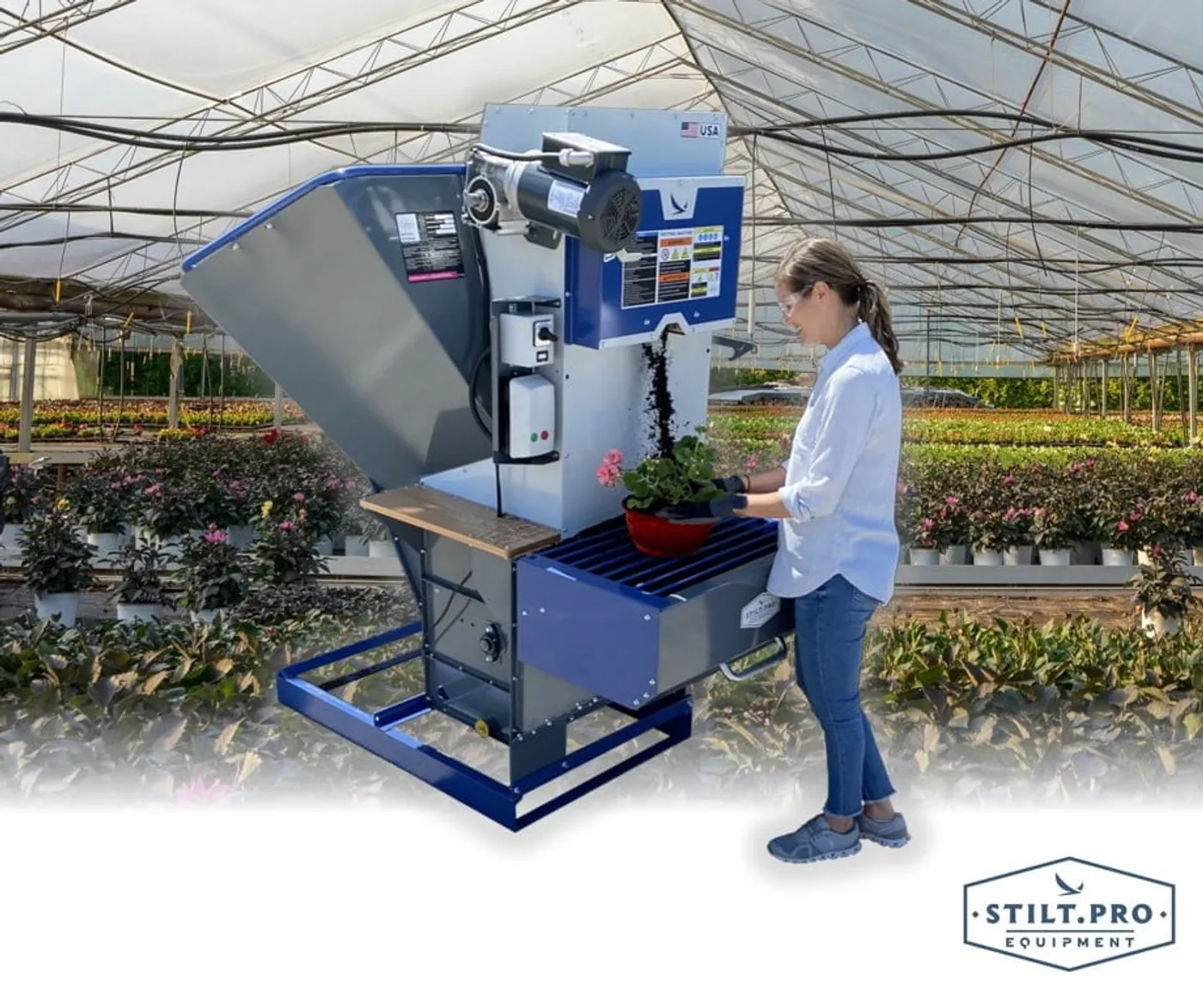 Grower potting a plant with a STILT.PRO potting machine in a greenhouse